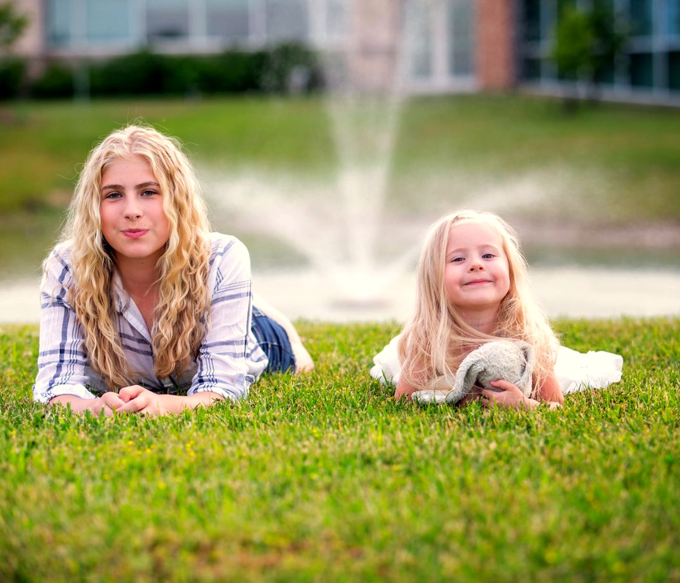 Two girls lying in grass, photographed in soft natural light